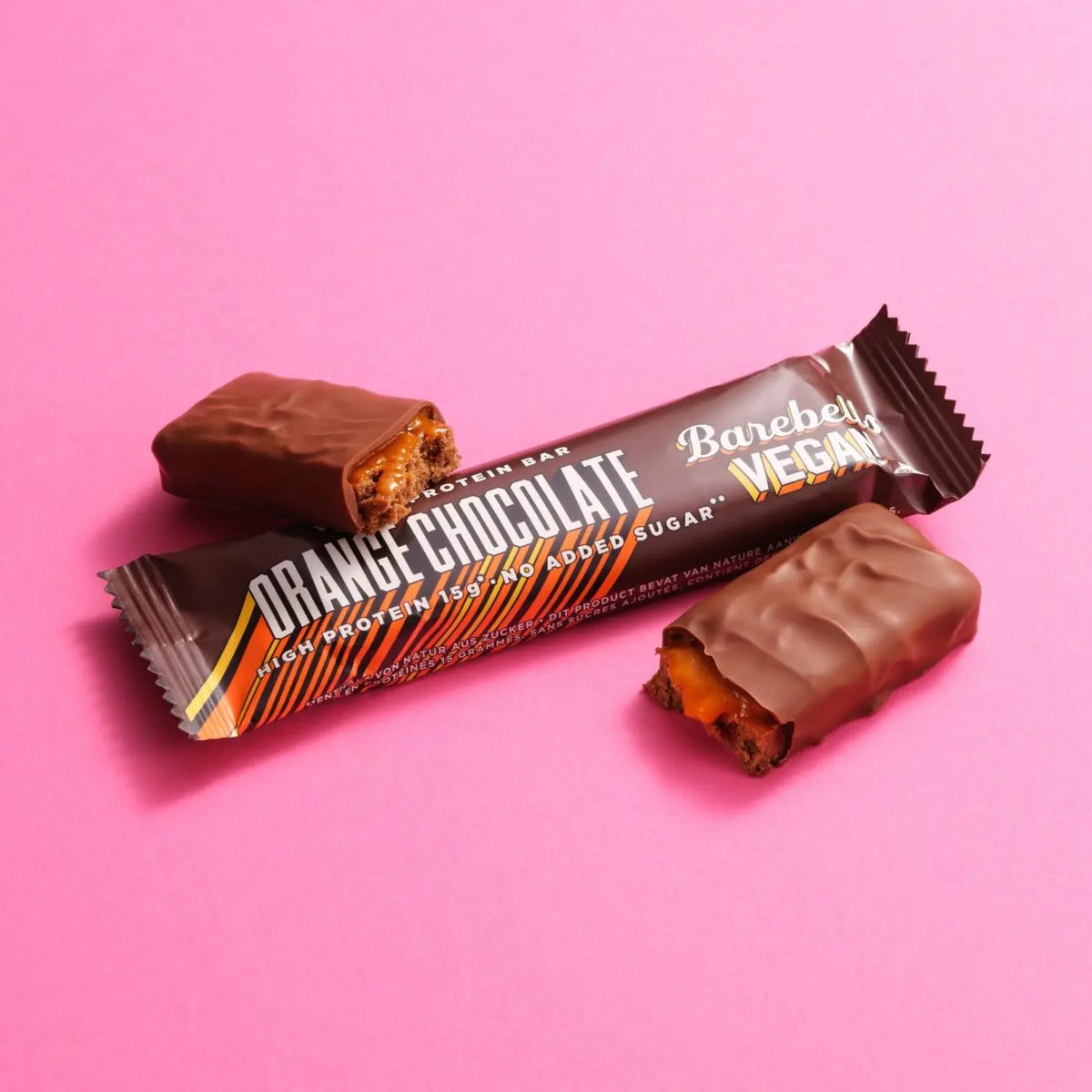 Vegane Protein Riegel Orange Schokolade, hochproteinhaltig, ohne zugesetzten Zucker, auf rosa Hintergrund