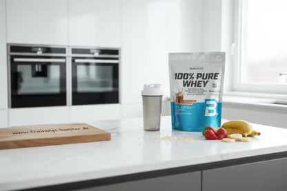 BioTechUSA 100% Pure Whey Protein mit Shaker, Banane und Erdbeeren auf Küchenarbeitsplatte