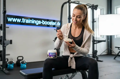 Frau isst Nussbutter im Fitnessstudio, ideal für Sportnahrung und Booster