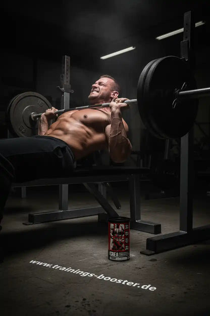 Muskulöser Mann beim Bankdrücken mit Kreatin-Booster im Fitnessstudio