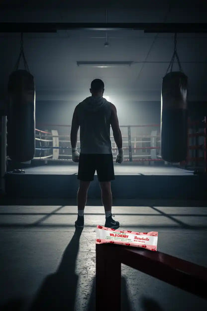 Boxer im Trainingsraum mit Wild Cherry Booster-Riegel für Sportnahrung und Energie