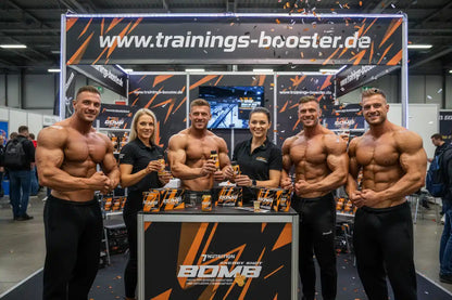 Muskulöse Athleten präsentieren Energy Shot Bomb auf Messestand mit trainings-booster.de