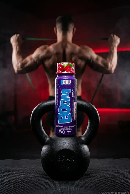 Trec Nutrition BOOM Pre Workout Shot Kirsch-Himbeere auf einer Kettlebell vor einem Bodybuilder