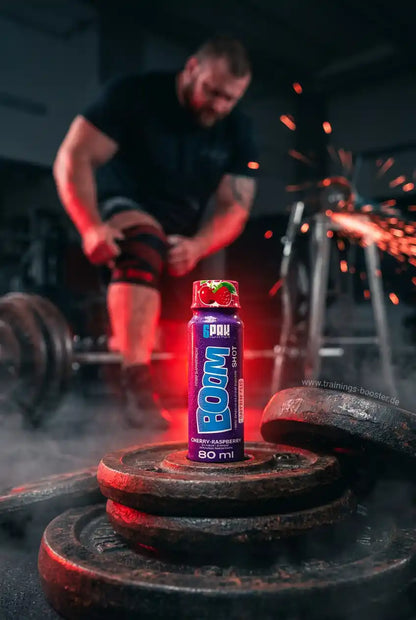 TREC NUTRITION BOOM Pre Workout Shot Kirsche-Himbeere auf Hantelscheiben im Fitnessstudio