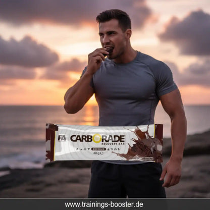 Muskulöser Mann isst FA Nutrition Carborade Recovery Bar Brownie vor einem Sonnenuntergang.