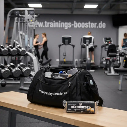 Sporttasche mit Haferiegel und Fitnesszubehör im Fitnessstudio, Hanteln und Cardiogeräte im Hintergrund