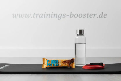 Proteinriegel, Wasserflasche und Widerstandsbänder auf Yogamatte für Fitness und Training