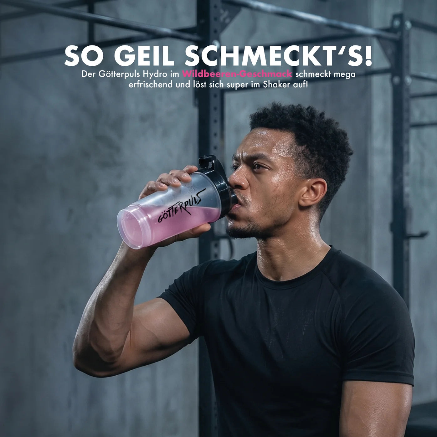 Muskulöser Mann trinkt pinken Göttelpuls Hydro Wildbeeren-Booster im Fitnessstudio
