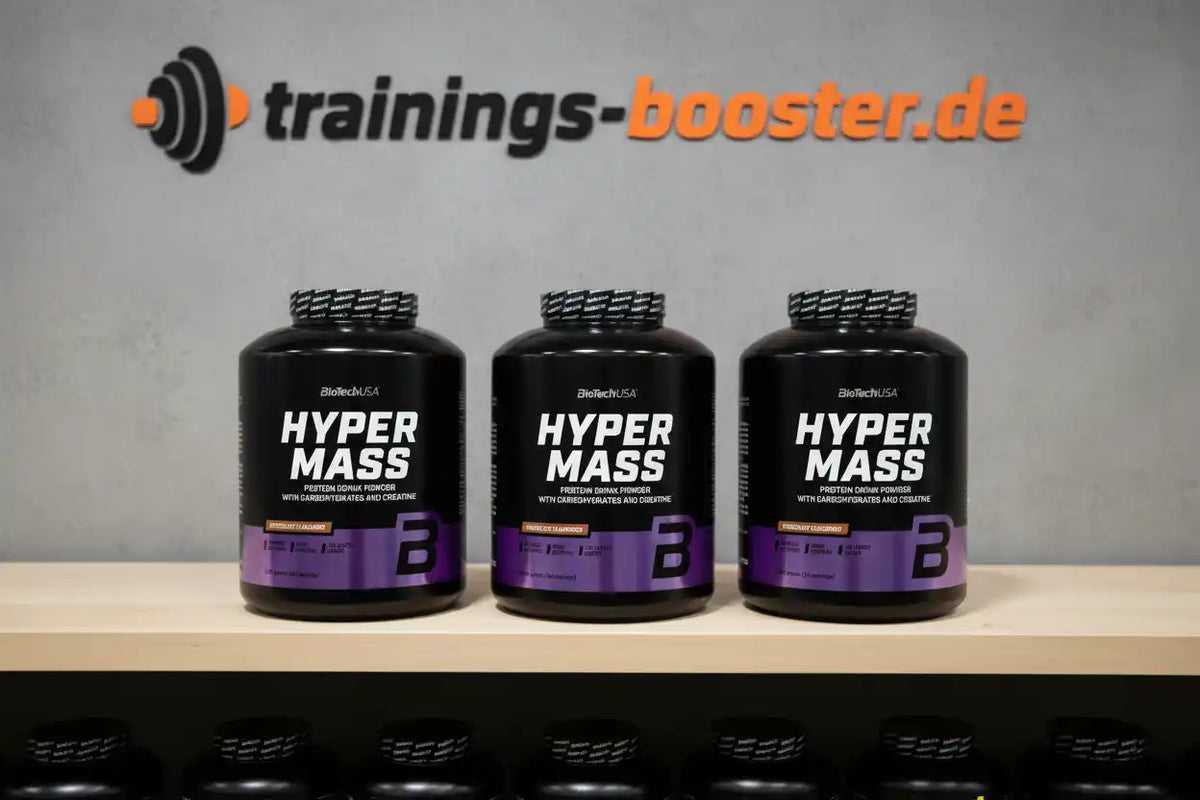 Drei BioTechUSA Hyper Mass Protein Powder Dosen vor trainings-booster.de Logo