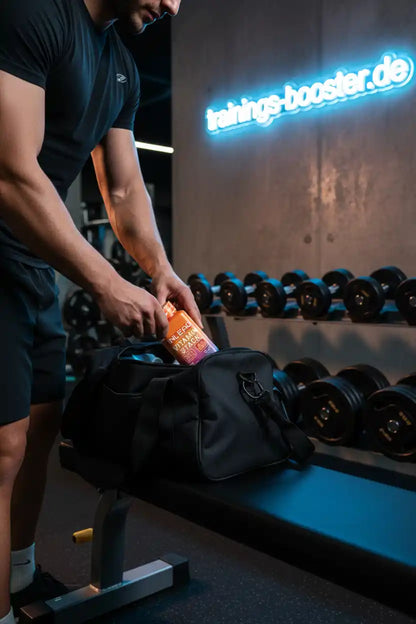 Muskulöser Mann packt INLEAG Vitamin Stack in Sporttasche im Fitnessstudio