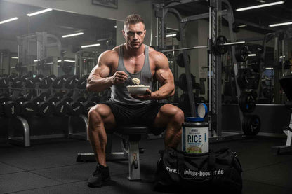 Muskulöser Mann isst Reiscreme im Fitnessstudio – ideal für Sportnahrung & Trainingsergänzung