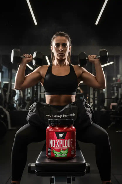 Muskulöse Frau mit Hanteln und BSN Nutrition N.O. XPLODE Pre Workout Booster im Fitnessstudio