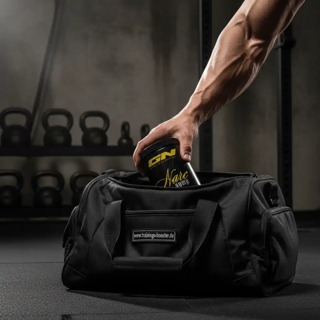 Muskulöser Arm legt GN Narc Pump Booster in schwarze Fitness-Tasche im Gym