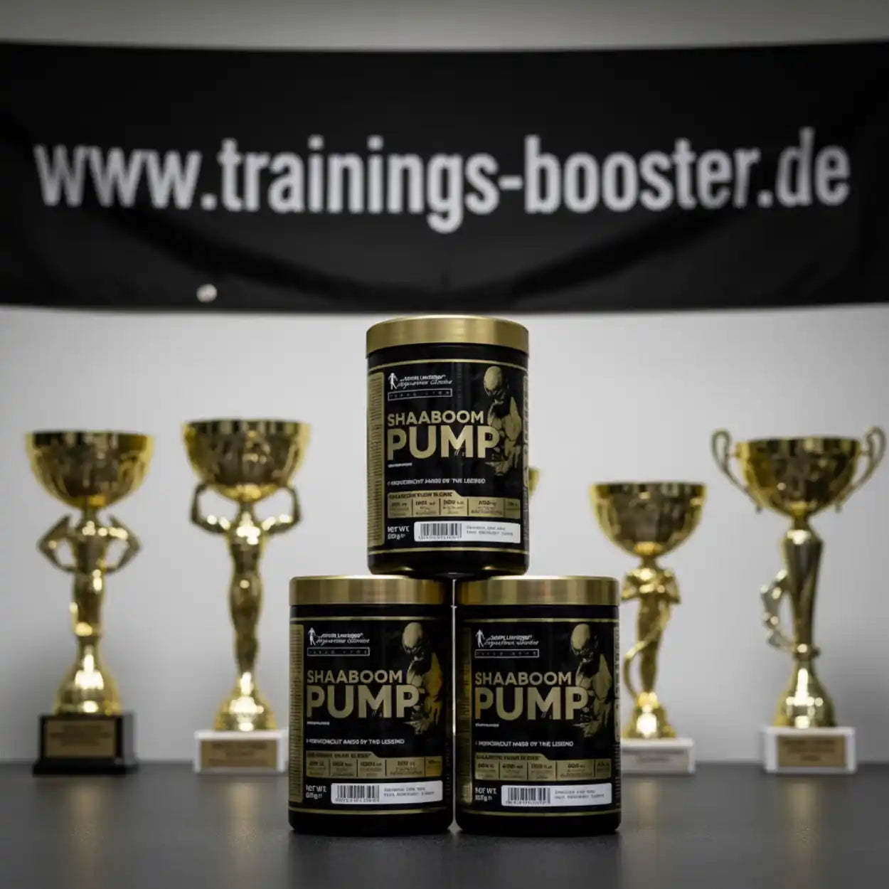 SHAABOOM PUMP Pre-Workout Booster mit goldenen Trophäen im Hintergrund – Sportnahrung für maximale Leistung